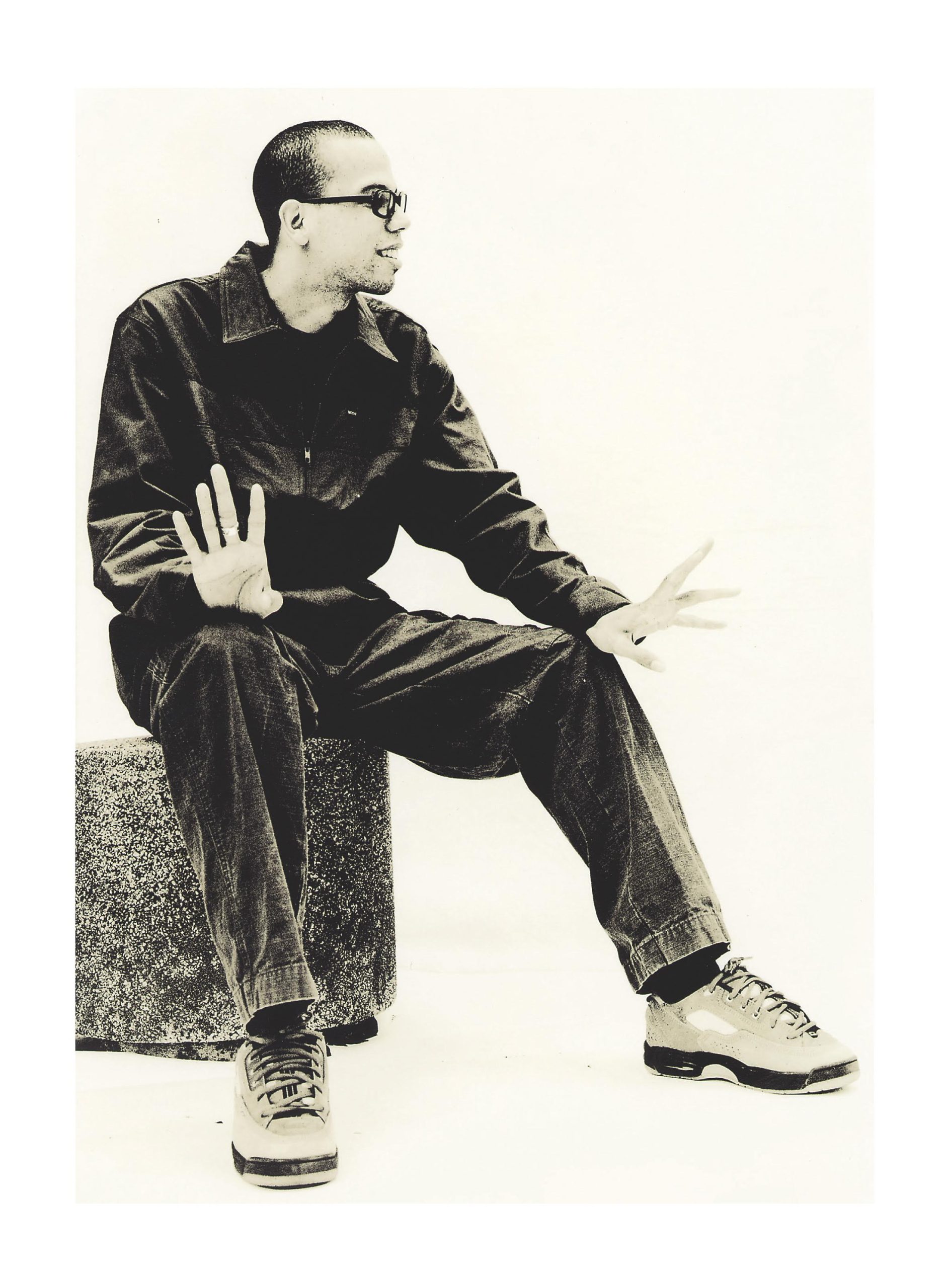 Analog lith print portrait of sitting man wearing glasses. Vertical studio shot.